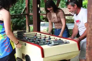 Des vacanciers s’amusant autour d’un baby-foot dans un camping à Aignan, ambiance conviviale et familiale.