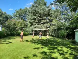 Partie de volley entre vacanciers sur une pelouse verdoyante d’un camping à Aignan, sous un ciel bleu d'été.